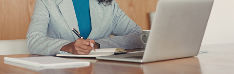 businesswoman writing in a notebook in front of her laptop. businesswoman writing in a notebook in front of her laptop.